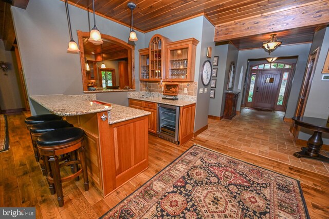 kitchen featuring wine cooler, wooden ceiling, light hardwood / wood-style floors, tasteful backsplash, and pendant lighting