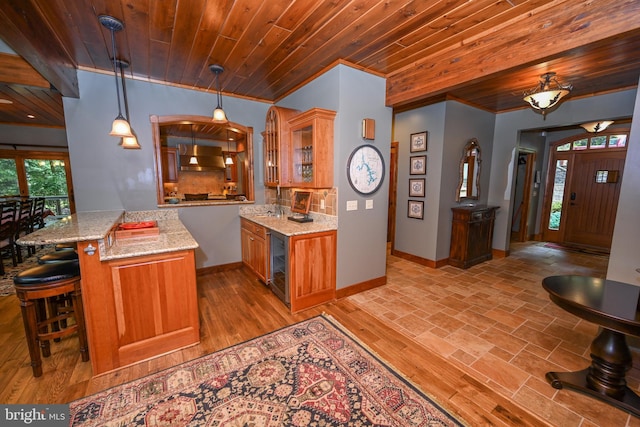 kitchen with a peninsula, brown cabinetry, glass insert cabinets, and a kitchen breakfast bar