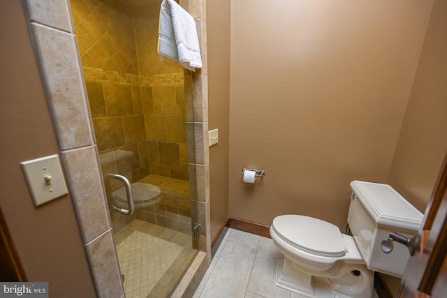 full bath with toilet, a stall shower, and baseboards