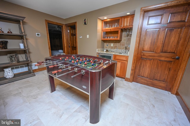 rec room with beverage cooler, indoor wet bar, a sink, and baseboards