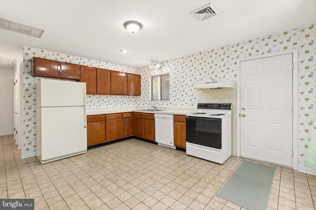 kitchen with light tile patterned flooring, white appliances, sink, and a textured ceiling