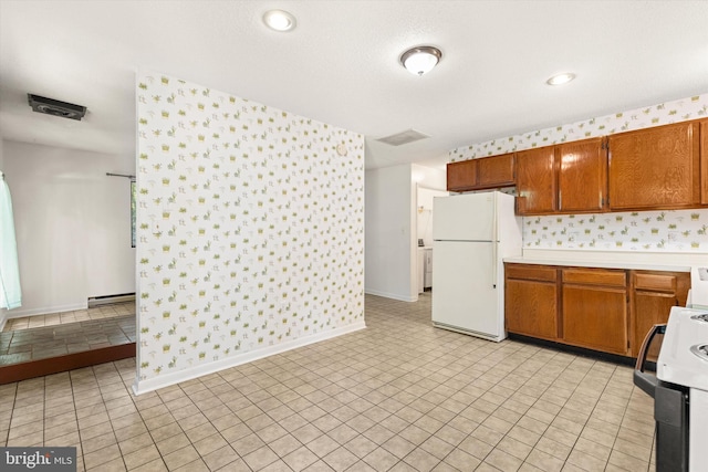 kitchen with range, white fridge, baseboard heating, and light tile patterned floors