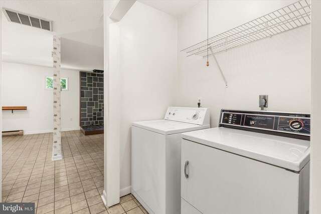 clothes washing area featuring a baseboard radiator, washer and clothes dryer, and light tile patterned floors