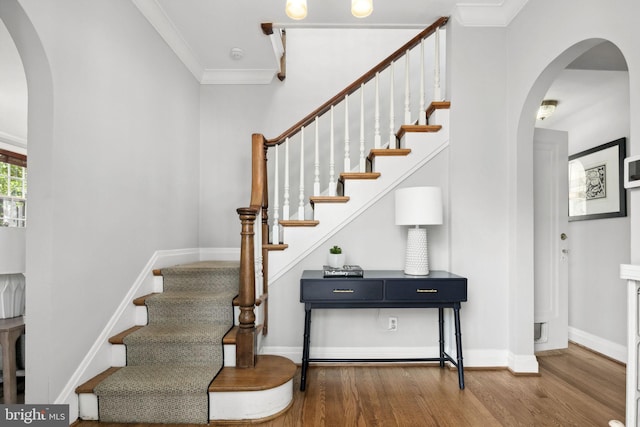 stairs with crown molding and wood-type flooring