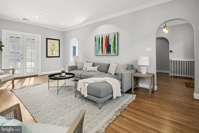 living room with wood-type flooring, radiator, crown molding, and french doors