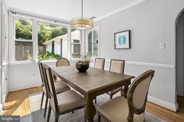 dining room with crown molding and light hardwood / wood-style floors