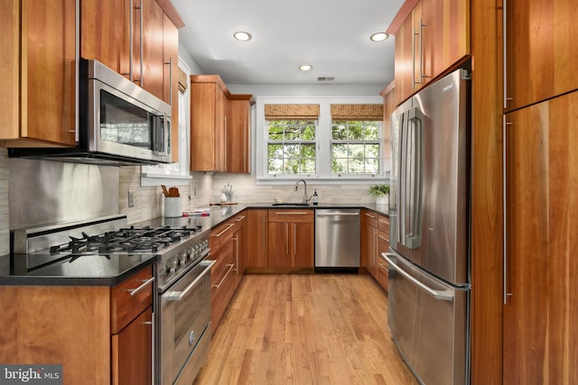 kitchen with light hardwood / wood-style floors, backsplash, stainless steel appliances, and sink