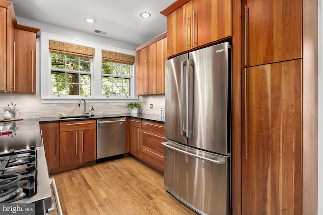 kitchen featuring stainless steel appliances, tasteful backsplash, sink, and light hardwood / wood-style floors