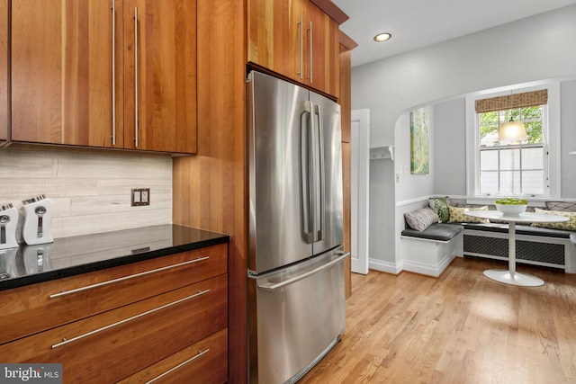 kitchen with stainless steel refrigerator, radiator, breakfast area, light hardwood / wood-style floors, and backsplash