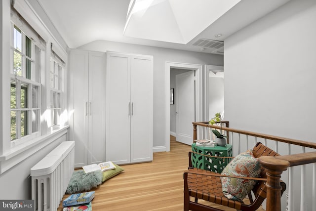 living area with lofted ceiling, radiator, and light wood-type flooring