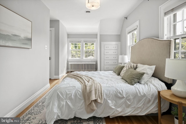 bedroom featuring hardwood / wood-style flooring and radiator heating unit