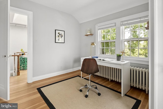 office area with hardwood / wood-style floors, radiator heating unit, and vaulted ceiling