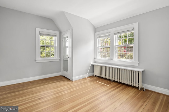 bonus room featuring radiator heating unit, wood-type flooring, and vaulted ceiling