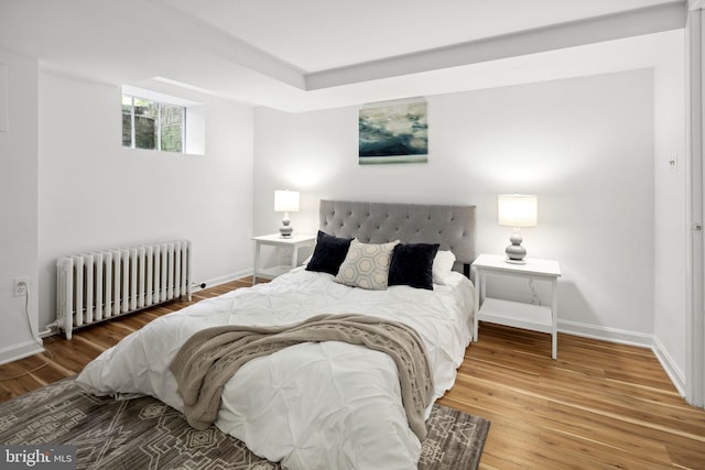 bedroom featuring radiator heating unit and hardwood / wood-style floors