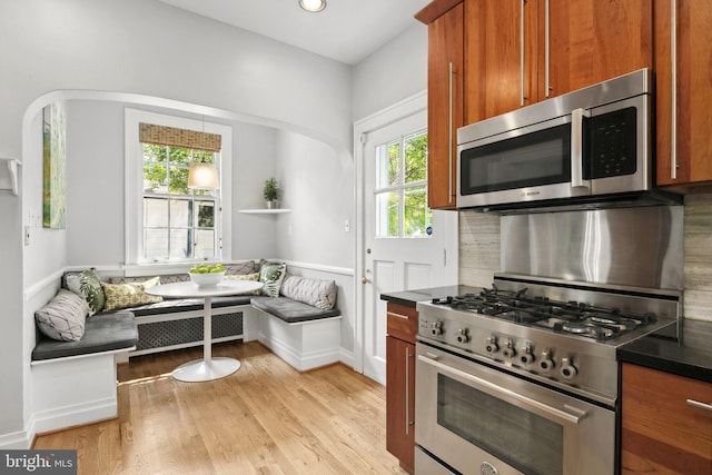 kitchen with breakfast area, appliances with stainless steel finishes, light hardwood / wood-style floors, and decorative backsplash