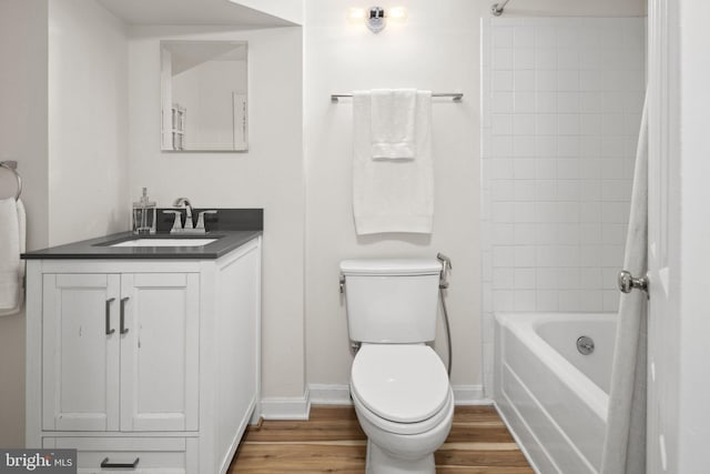 full bathroom featuring vanity, tiled shower / bath, hardwood / wood-style floors, and toilet