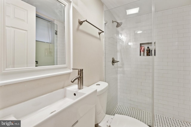 bathroom featuring toilet, a tile shower, and vanity