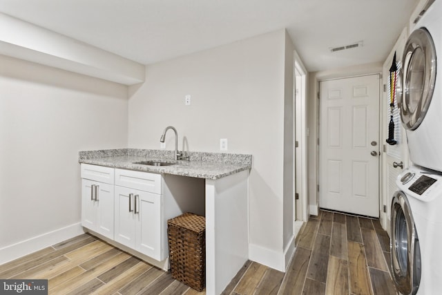 clothes washing area featuring cabinets, sink, and stacked washer / drying machine