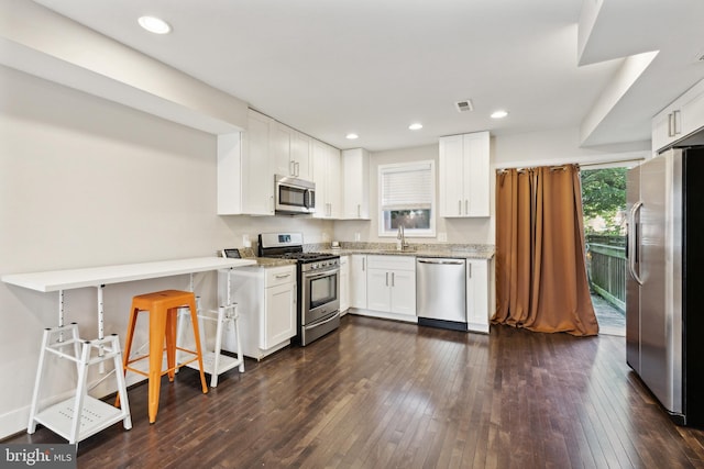 kitchen featuring white cabinets, appliances with stainless steel finishes, sink, dark hardwood / wood-style floors, and light stone counters