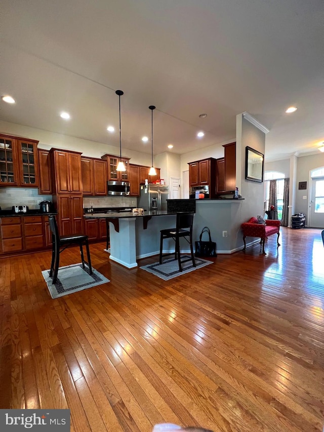 kitchen featuring pendant lighting, stainless steel appliances, dark wood-type flooring, and a breakfast bar area