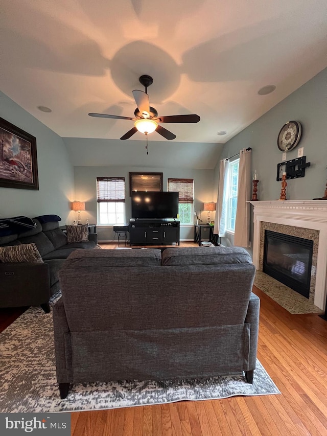 living room with ceiling fan, lofted ceiling, a fireplace, and light hardwood / wood-style floors