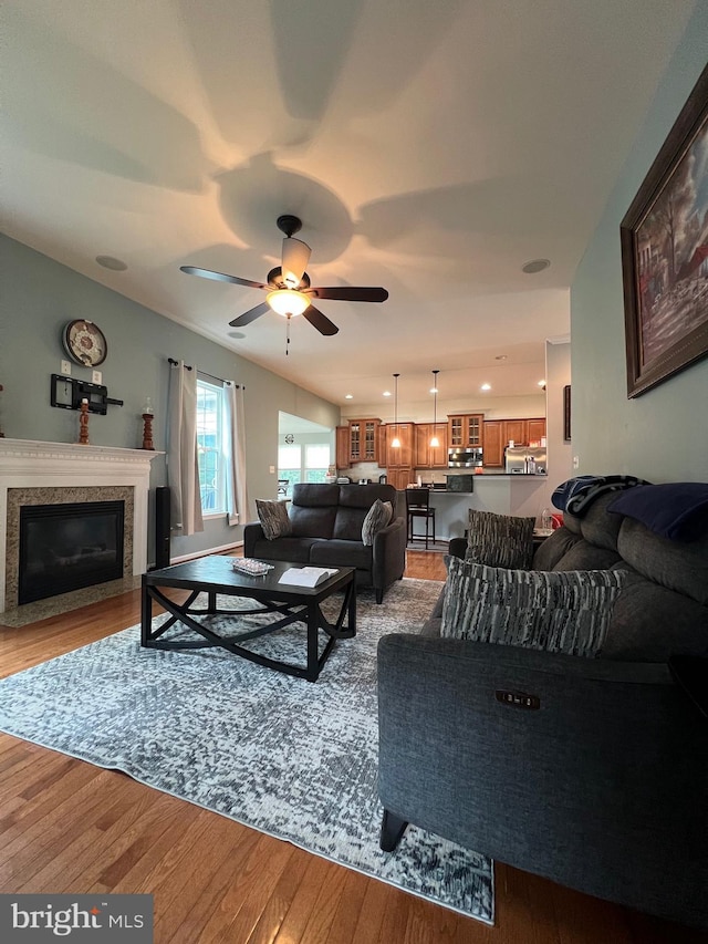 living room with a premium fireplace, hardwood / wood-style floors, and ceiling fan