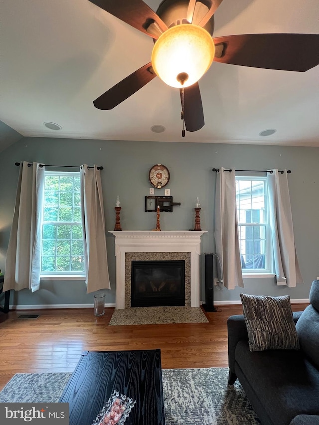 living room with a wealth of natural light, a high end fireplace, and wood-type flooring