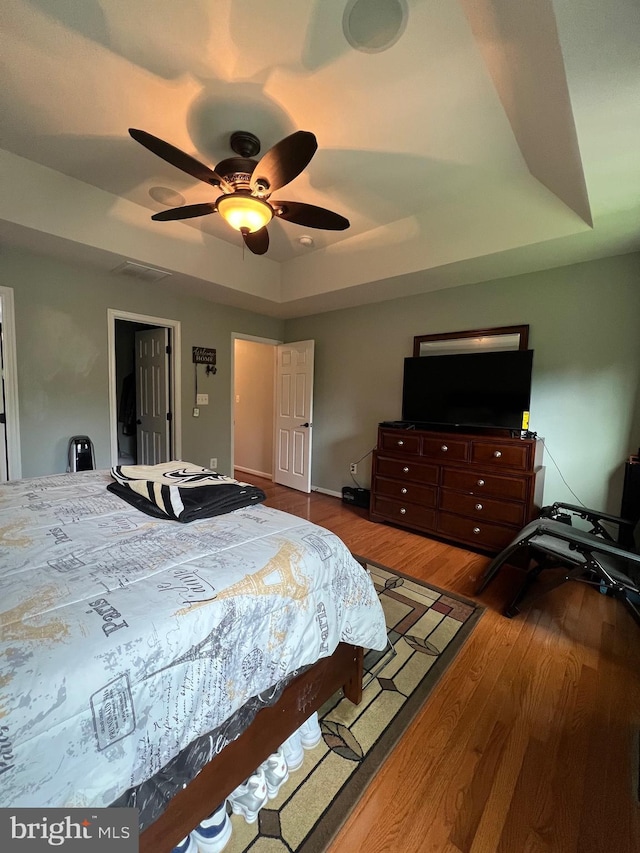 bedroom featuring a raised ceiling, hardwood / wood-style floors, and ceiling fan