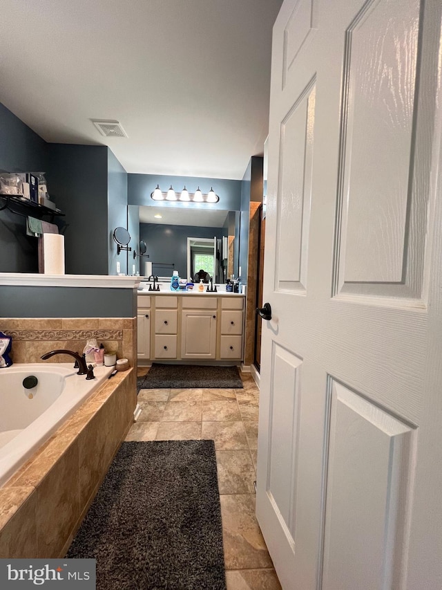 bathroom featuring vanity and tiled tub