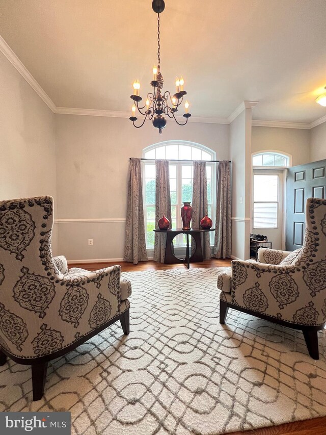 living area featuring an inviting chandelier, hardwood / wood-style floors, and ornamental molding