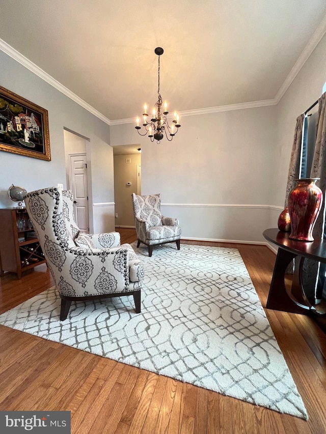 sitting room with an inviting chandelier, ornamental molding, and wood-type flooring