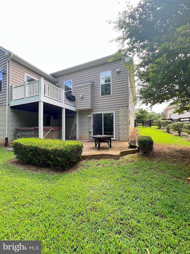 back of property with a yard, a hot tub, a patio, and a balcony