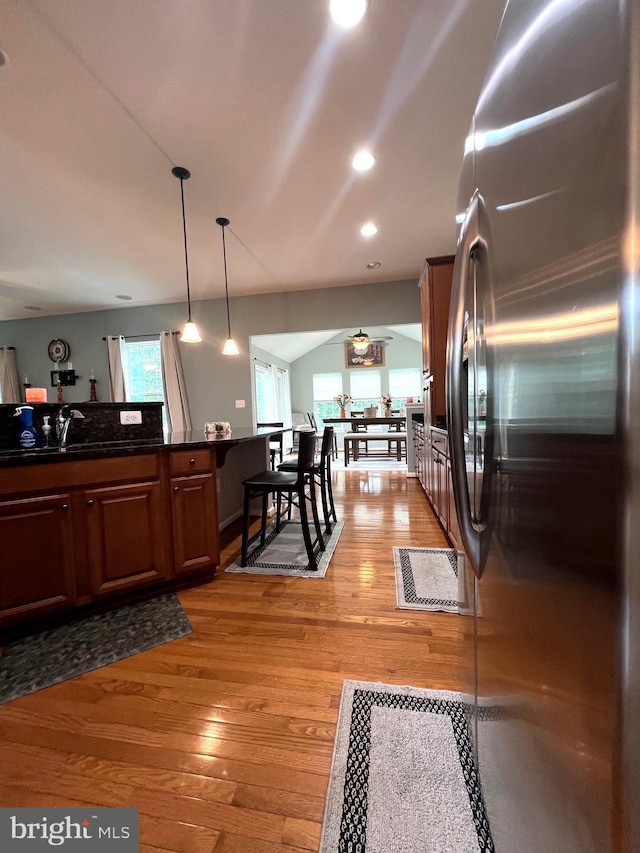 kitchen featuring sink, light hardwood / wood-style flooring, stainless steel fridge, and decorative light fixtures