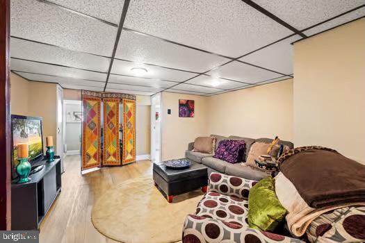 living room featuring light hardwood / wood-style flooring and a paneled ceiling