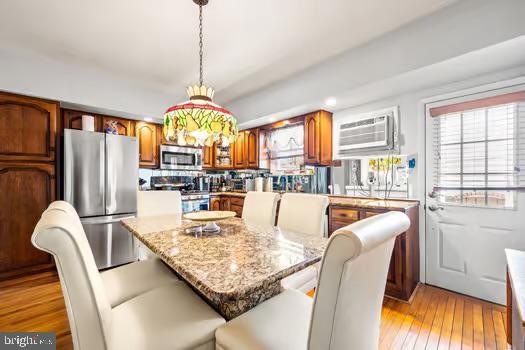 kitchen with a breakfast bar area, light hardwood / wood-style flooring, stainless steel appliances, hanging light fixtures, and plenty of natural light