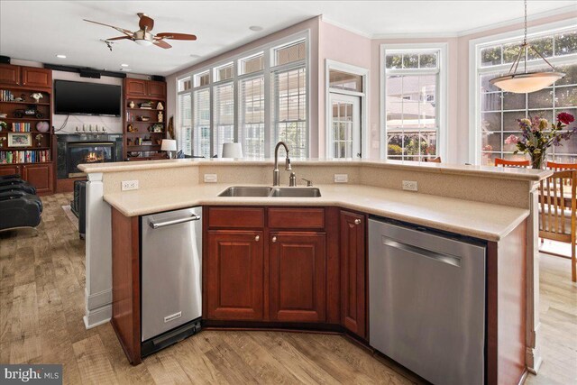 kitchen featuring sink, stainless steel dishwasher, light wood-type flooring, and hanging light fixtures