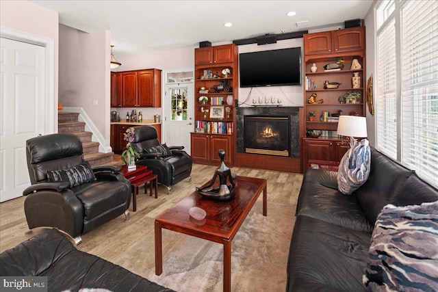 living room featuring light hardwood / wood-style flooring, a high end fireplace, and a healthy amount of sunlight