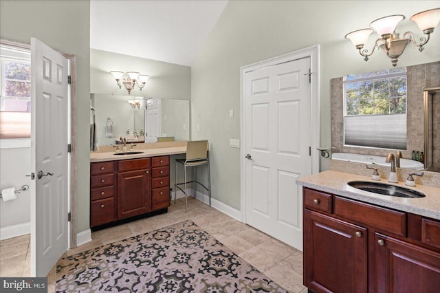 bathroom featuring tile patterned floors, an inviting chandelier, vaulted ceiling, and vanity