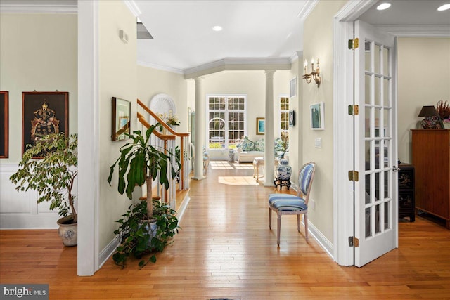 interior space with light wood-type flooring, decorative columns, ornamental molding, and french doors