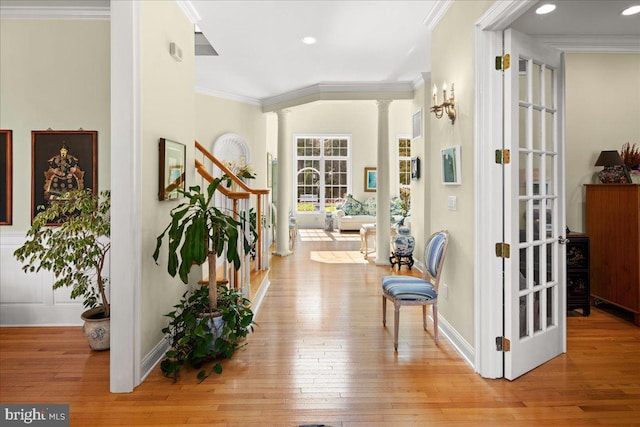 corridor with crown molding, light hardwood / wood-style flooring, and ornate columns