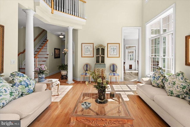 living room with hardwood / wood-style flooring, decorative columns, and a towering ceiling