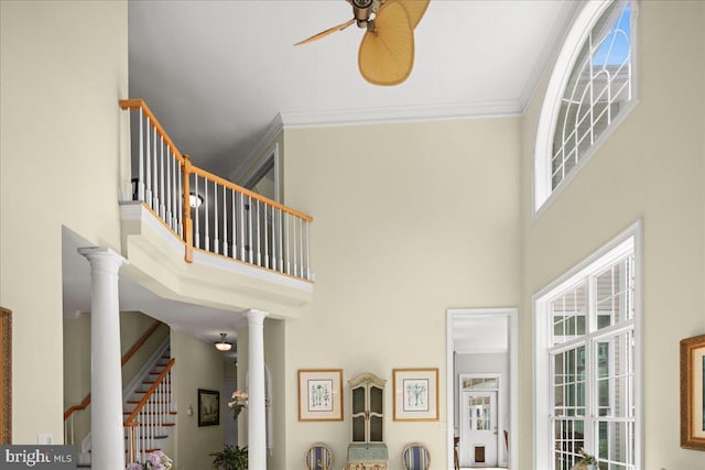 stairway featuring ceiling fan, decorative columns, ornamental molding, and a towering ceiling