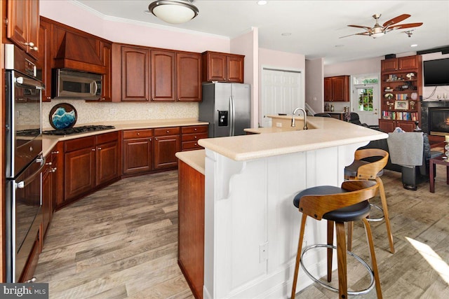 kitchen featuring a kitchen breakfast bar, a center island with sink, tasteful backsplash, and stainless steel appliances