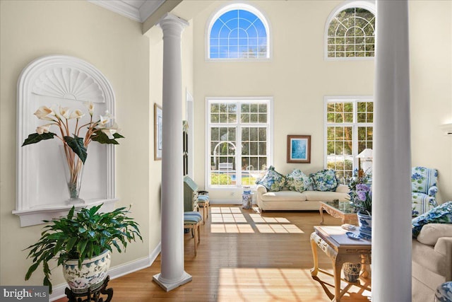 living room with light wood-type flooring, decorative columns, and a high ceiling