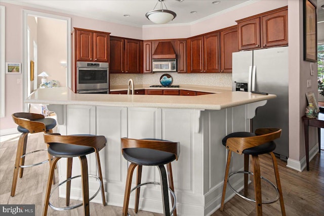 kitchen with decorative backsplash, a breakfast bar area, light hardwood / wood-style flooring, and stainless steel appliances