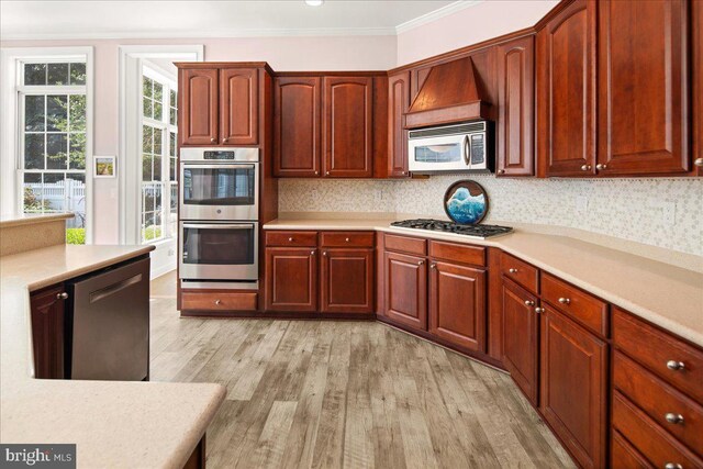 kitchen featuring crown molding, light hardwood / wood-style flooring, and appliances with stainless steel finishes