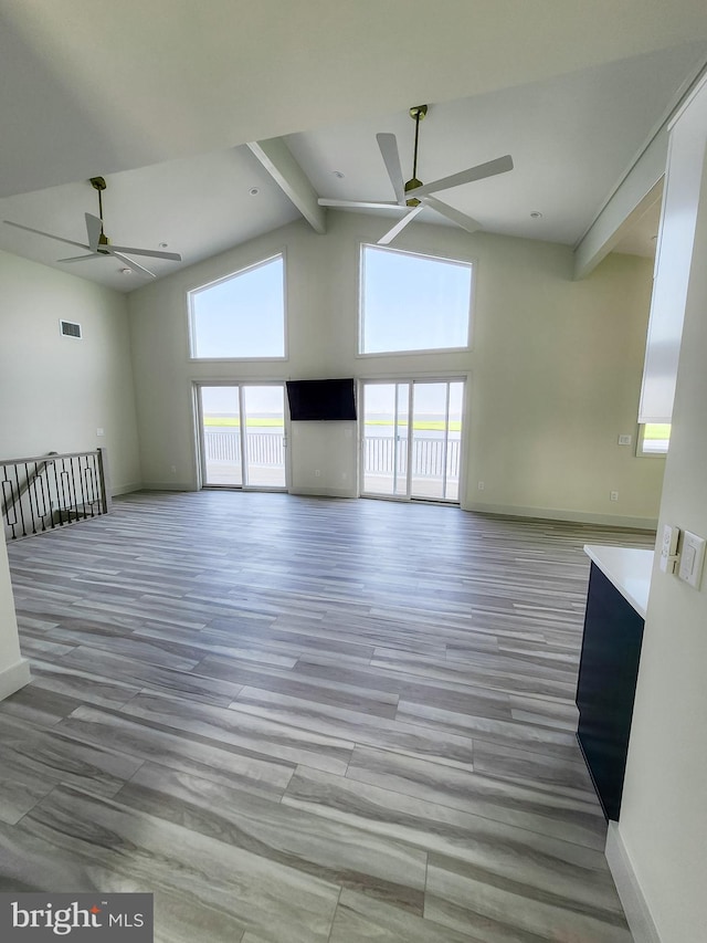 unfurnished living room featuring beam ceiling, light hardwood / wood-style floors, high vaulted ceiling, and ceiling fan