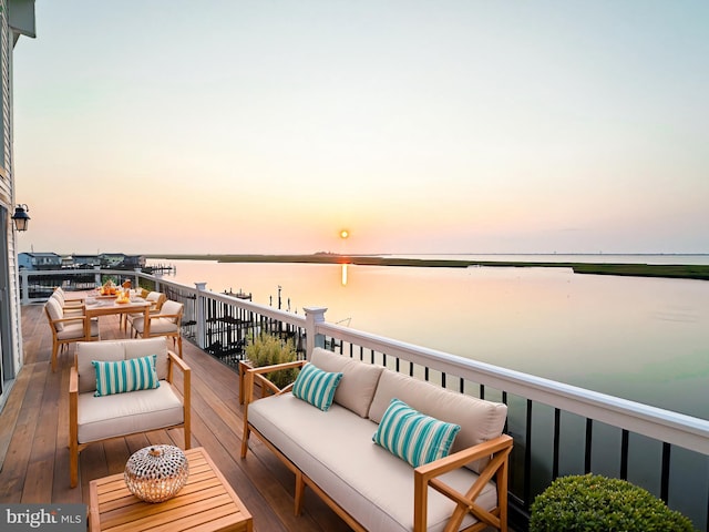 balcony at dusk featuring a water view and outdoor lounge area