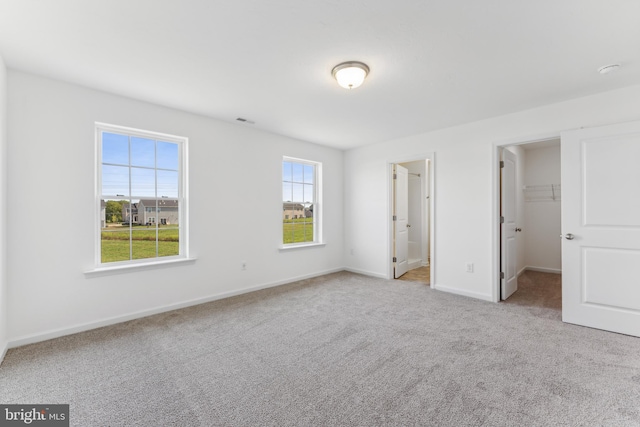 unfurnished bedroom featuring visible vents, baseboards, a closet, carpet, and a walk in closet