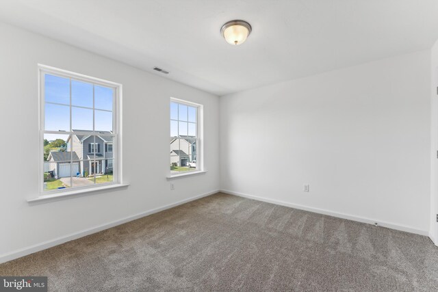 unfurnished room featuring carpet floors, visible vents, and baseboards